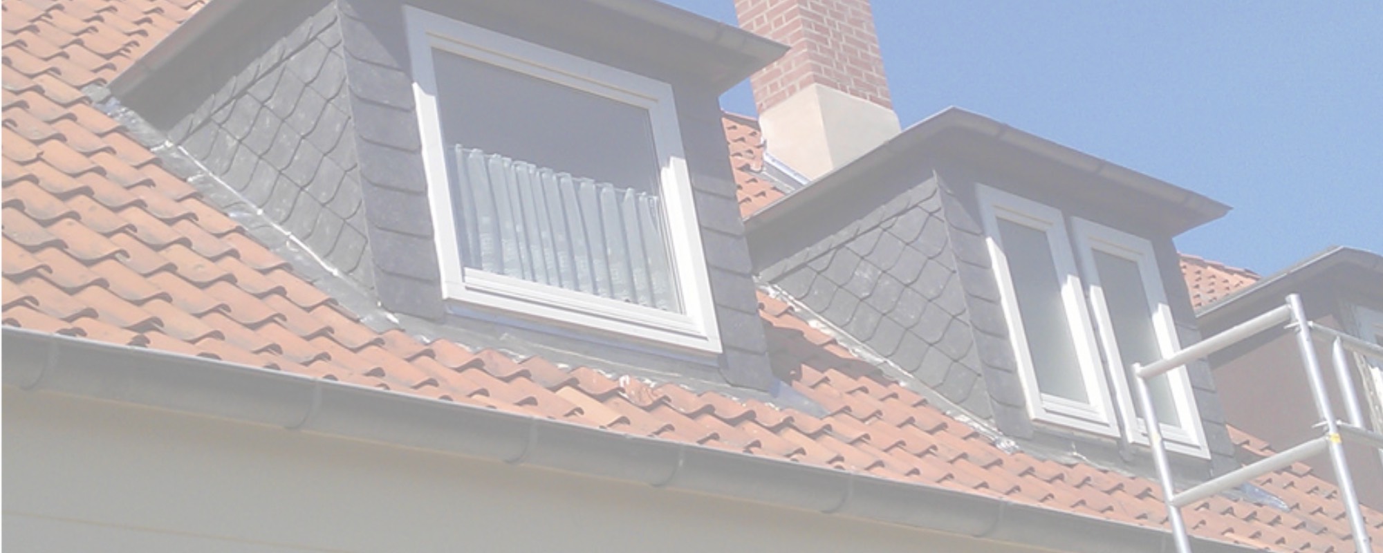 Perfekt verarbeitete Schiefergaube vor blauem Himmel